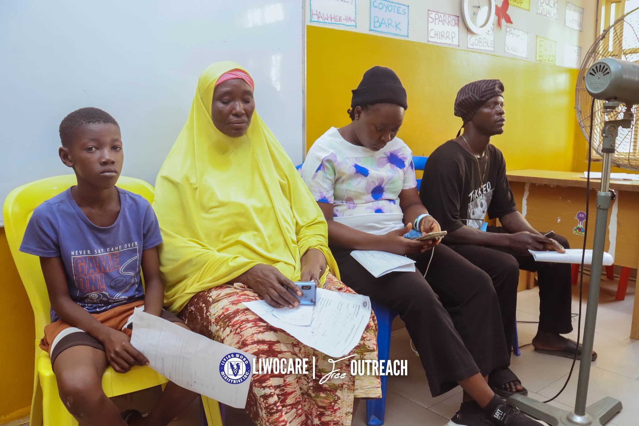 Four people sit in a row of chairs waiting to be attended to