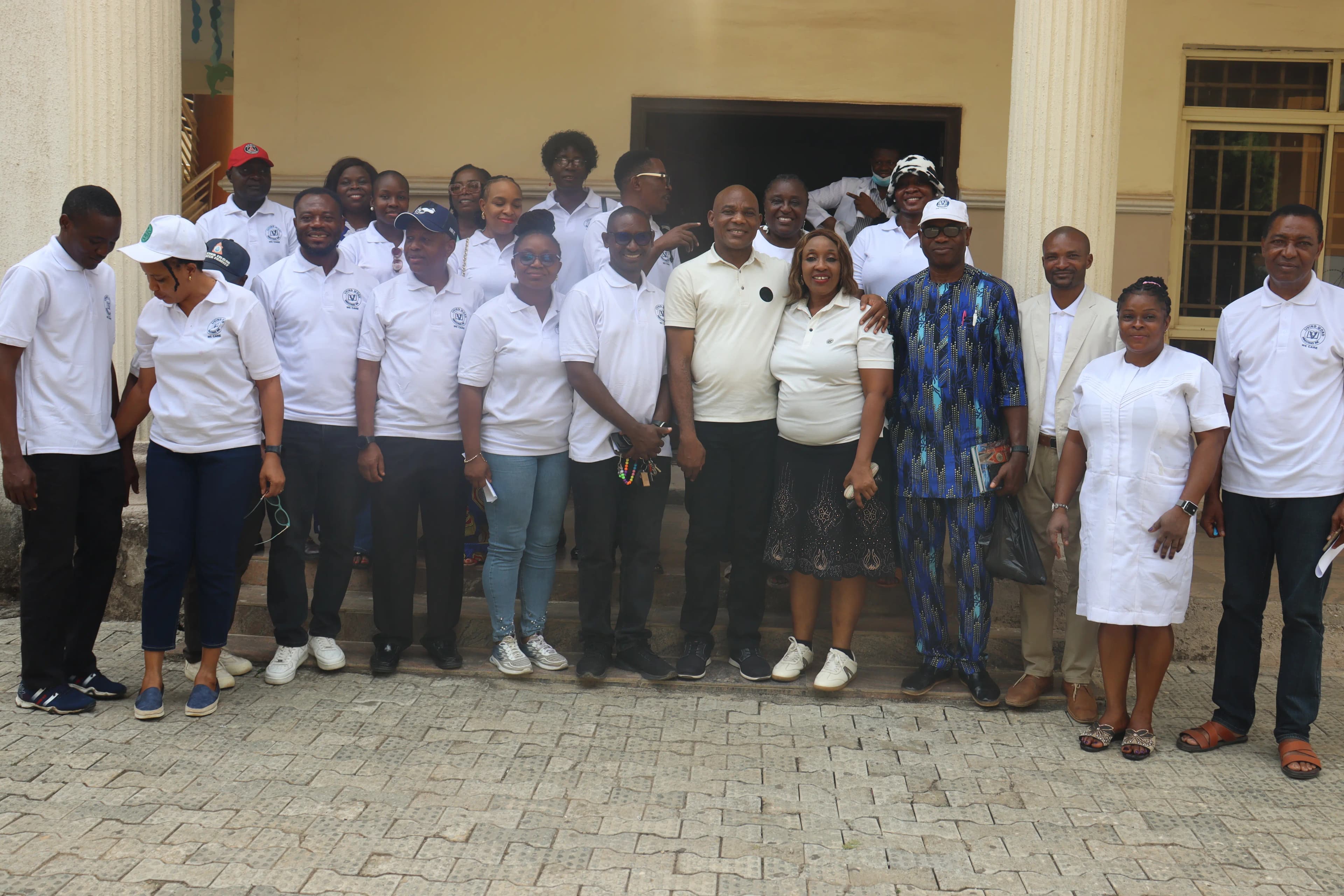 A large group of volunteers and organizers, pose for a group photo in front of a building.