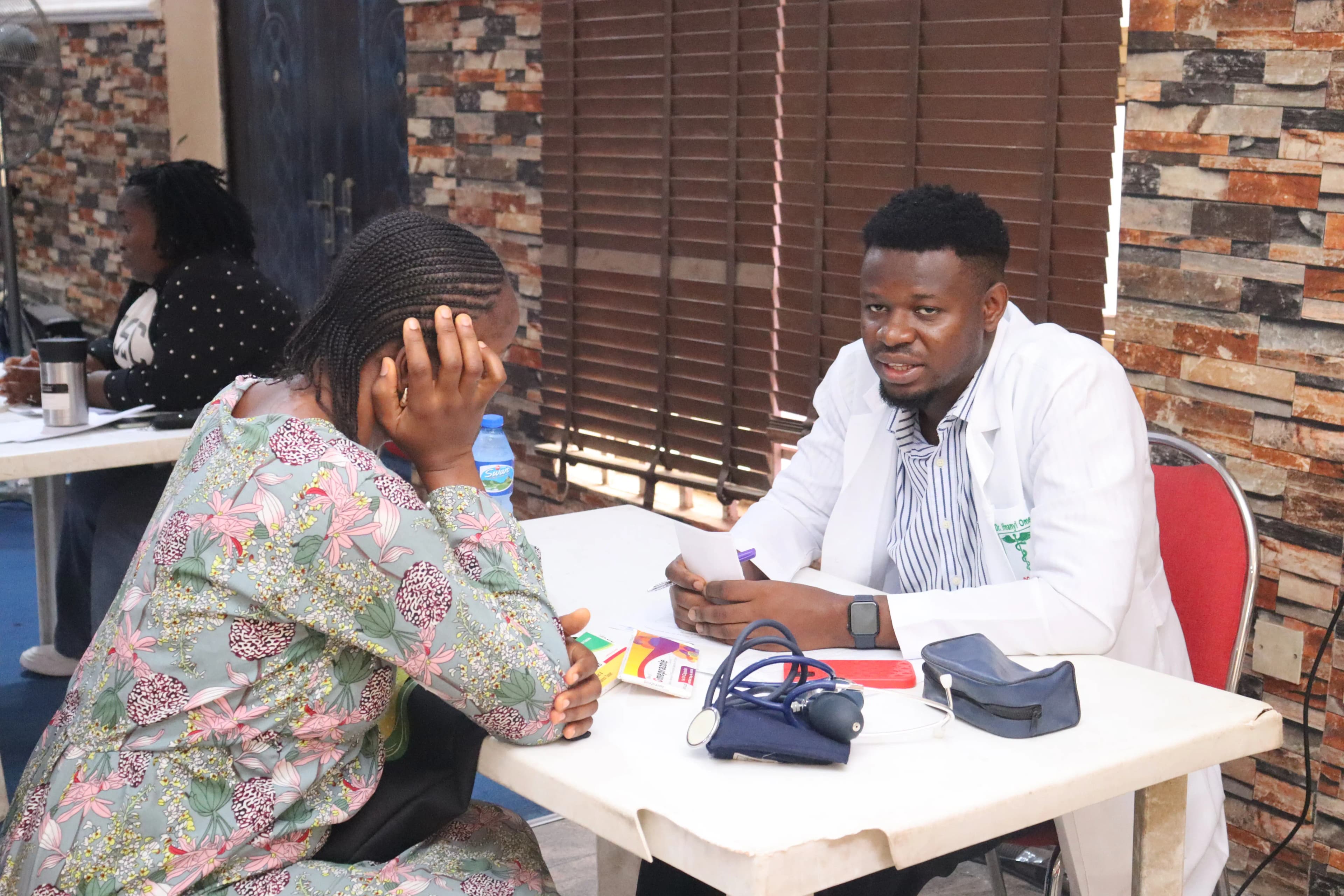 A medical consultant attending to a woman supporting her head on her arm, sitting across from him